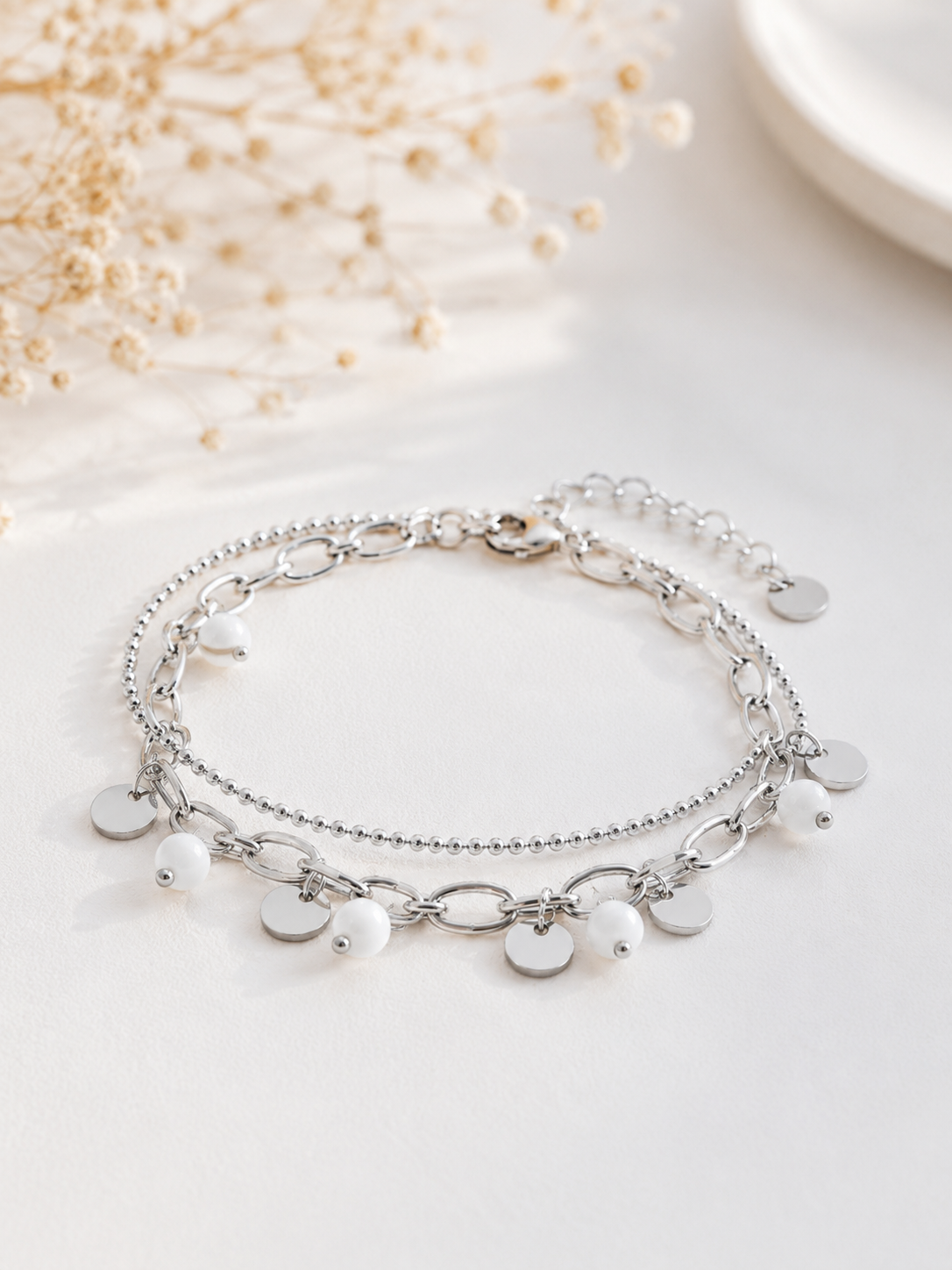Bracelet Lilo argenté double chaîne avec pampilles argentées et perles blanches dans un univers minimaliste et raffiné