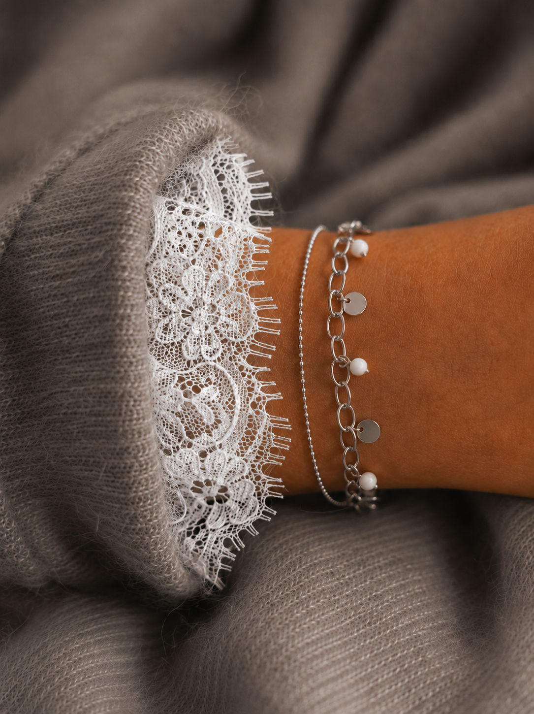 Bracelet Lilo argenté porté avec maille grise douce et dentelle blanche, style féminin chic et raffiné