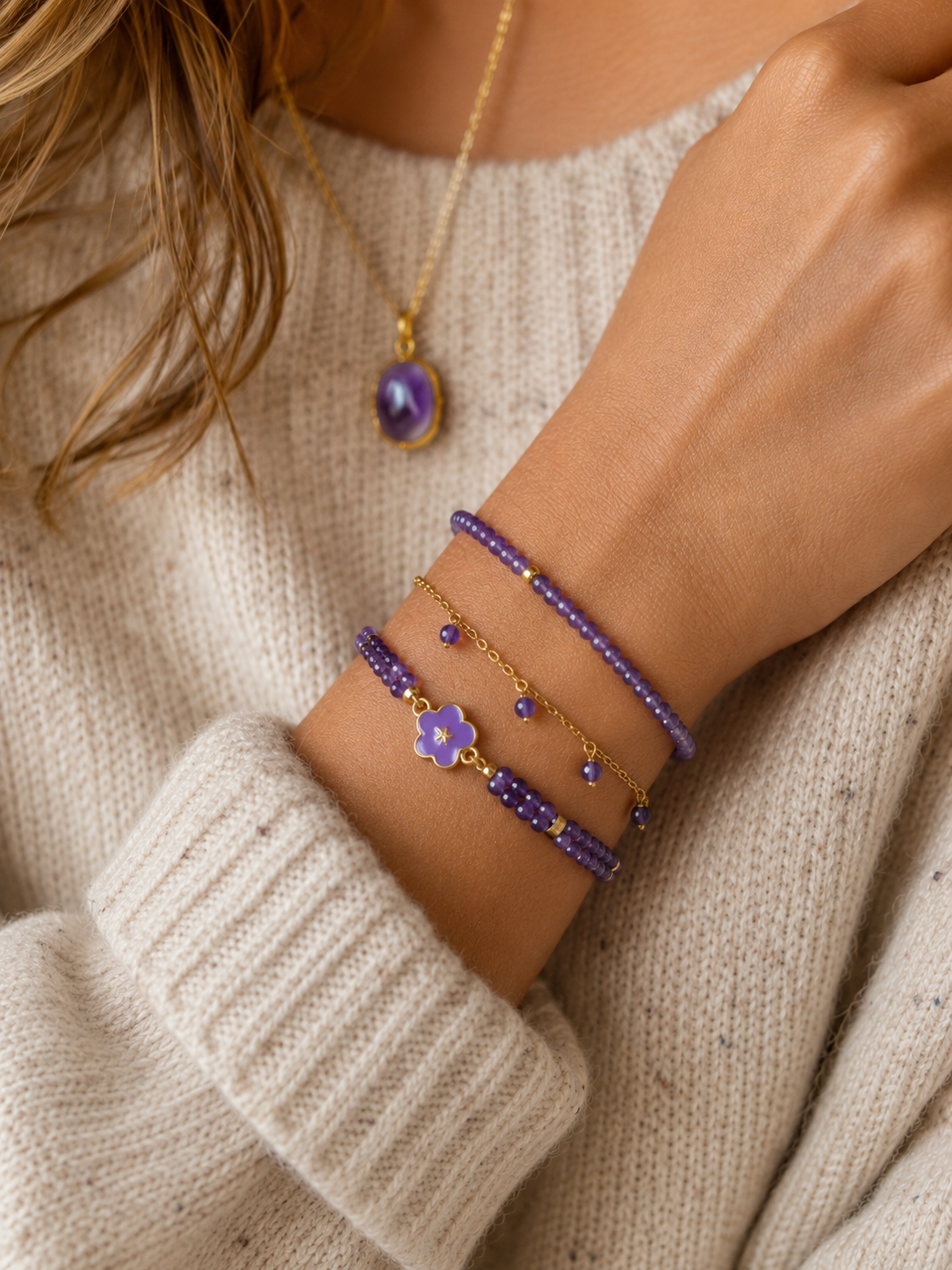Accumulation de bracelets lilas et dorés portés avec pull crème cosy
