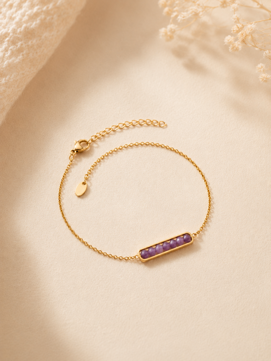 Bracelet Velia violet lavande et doré pour femme sur fond beige doux et chaleureux