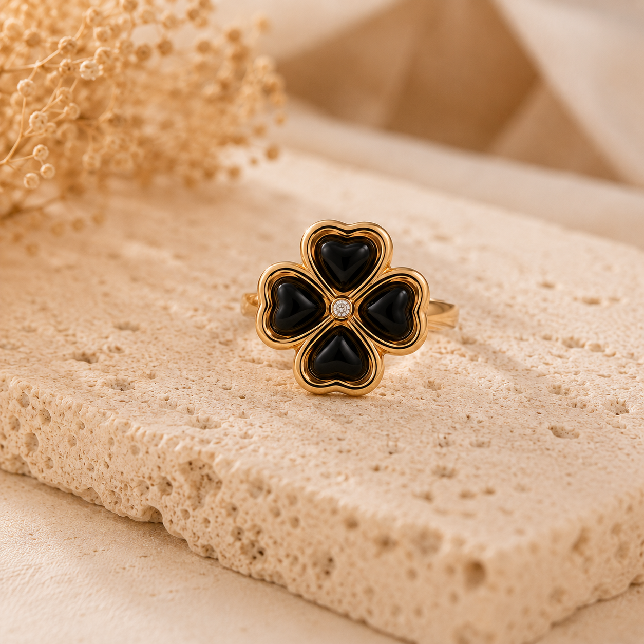 Bague Banga noire et dorée posée sur pierre naturelle beige – bague femme chic et chaleureuse Bella Cosa