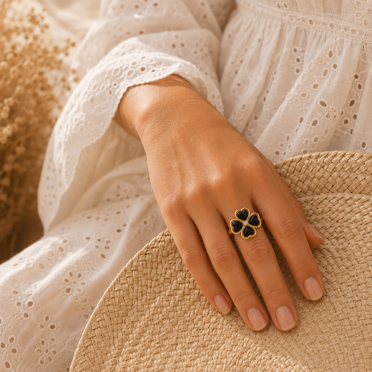 Main portant la bague Banga noire et dorée avec robe en broderie anglaise et panier tressé – bijou femme élégant Bella Cosa