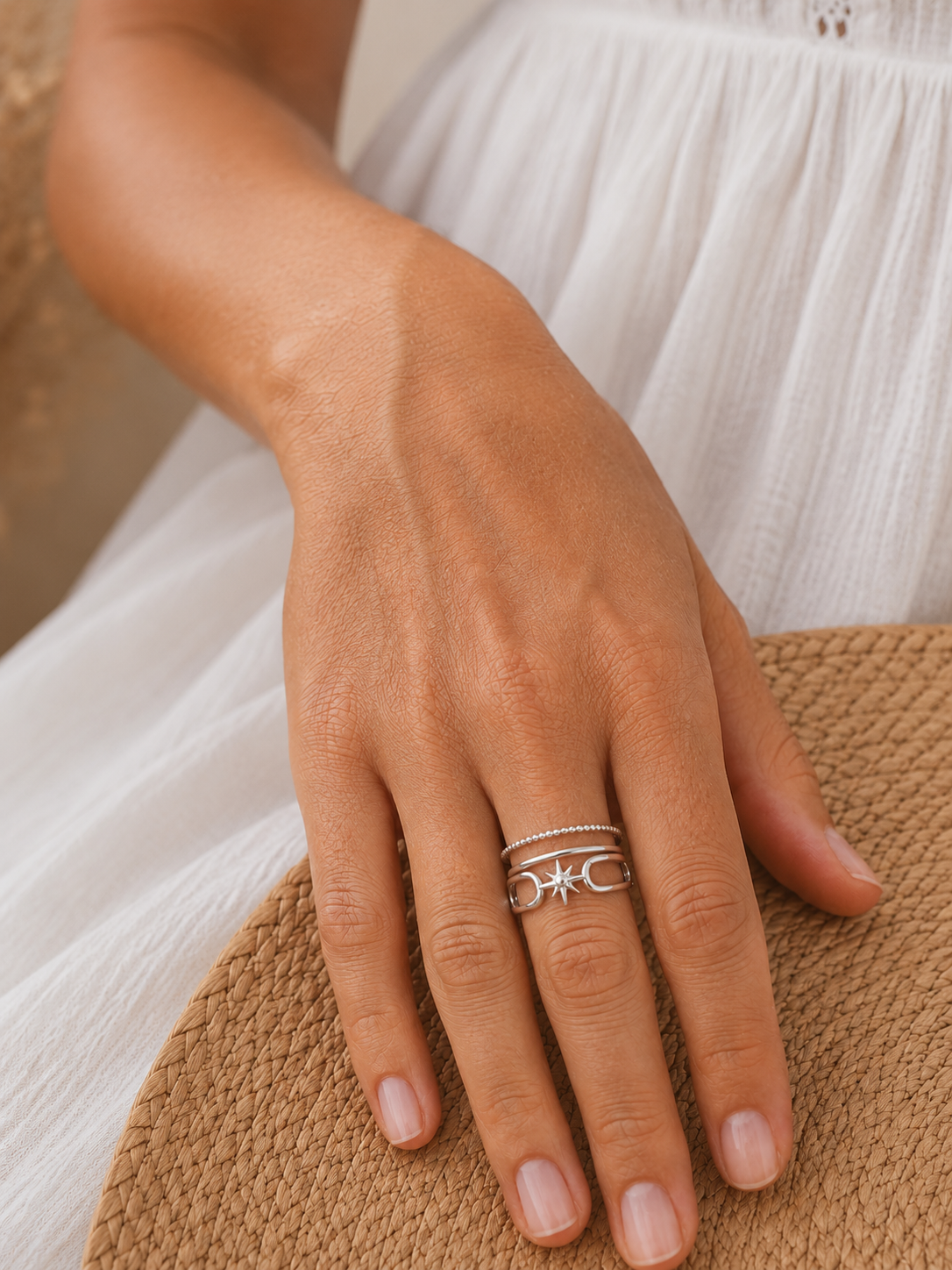 Main portant la bague Inès argentée avec robe blanche en lin et panier tressé – bijou femme bohème chic Bella Cosa