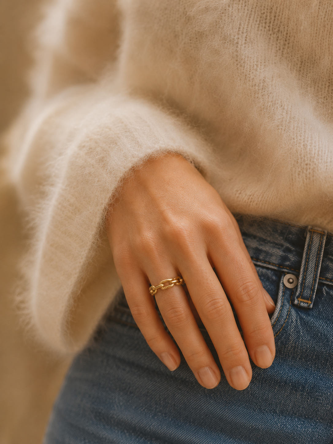 Main portant la bague Opale dorée avec pull beige mohair et jean bleu – bijou femme chaleureux Bella Cosa