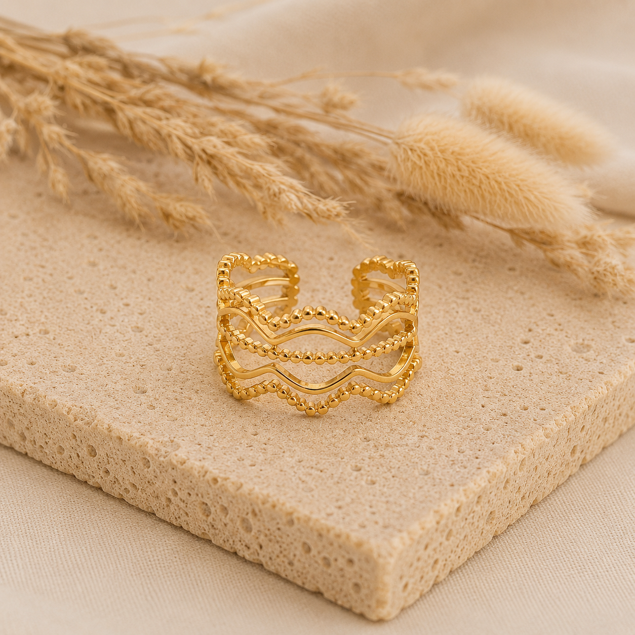 Bague Olga dorée effet perlé posée sur pierre naturelle beige dans une ambiance douce et chaleureuse – Bella Cosa