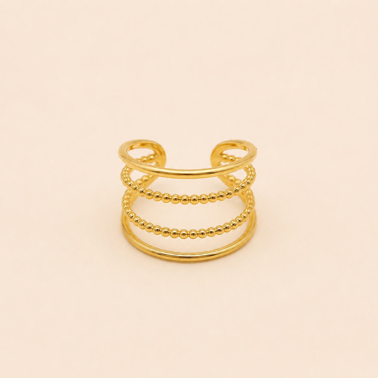 Bague Orane dorée à quatre anneaux dont deux perlés sur fond crème minimaliste – bijou femme élégant Bella Cosa