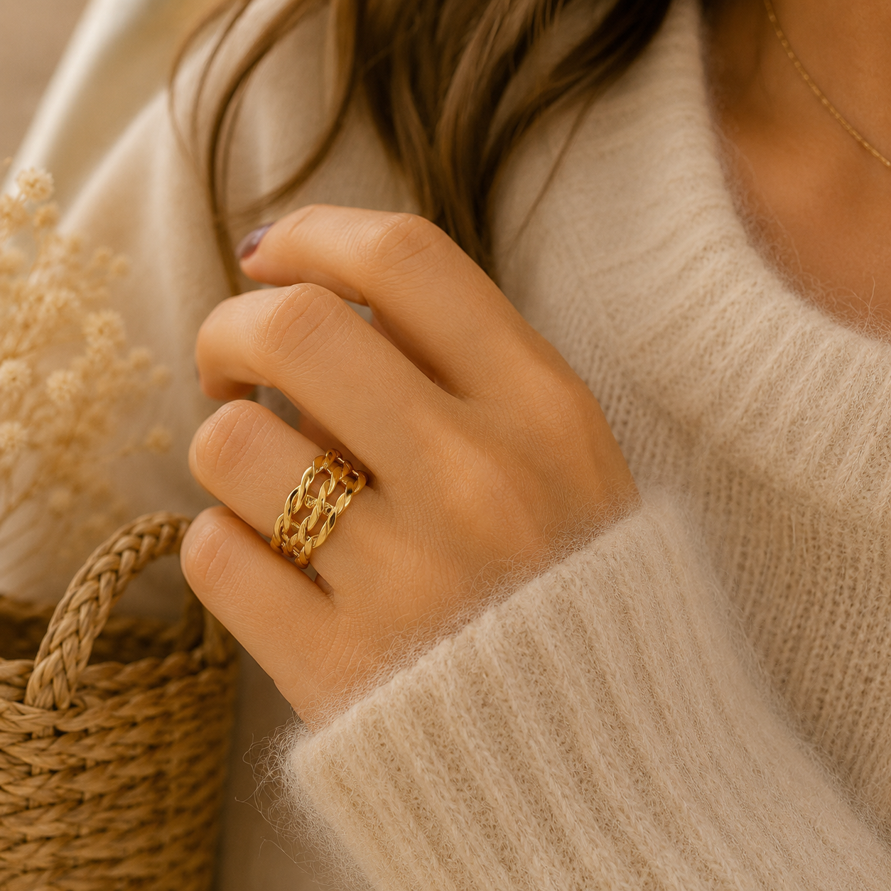 Main portant la bague Osana dorée à maille allongée avec pull mohair beige dans une ambiance douce et naturelle – bijou femme Bella Cosa