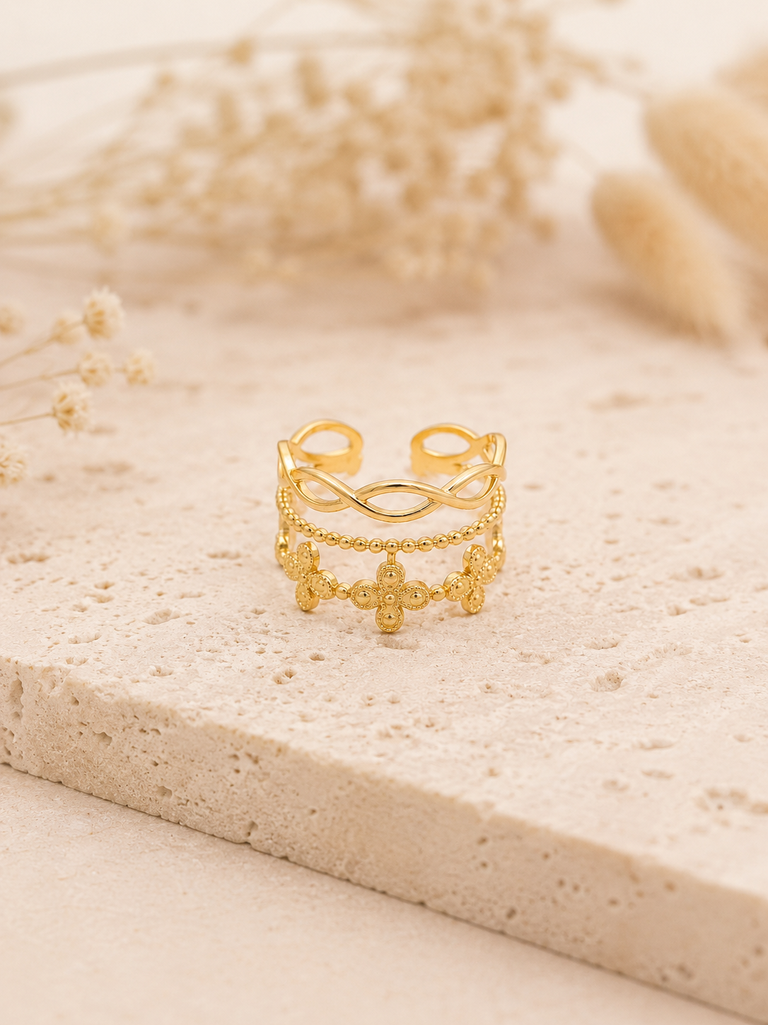 Bague Obella dorée posée sur travertin beige dans une ambiance naturelle et lumineuse – bijou femme Bella Cosa