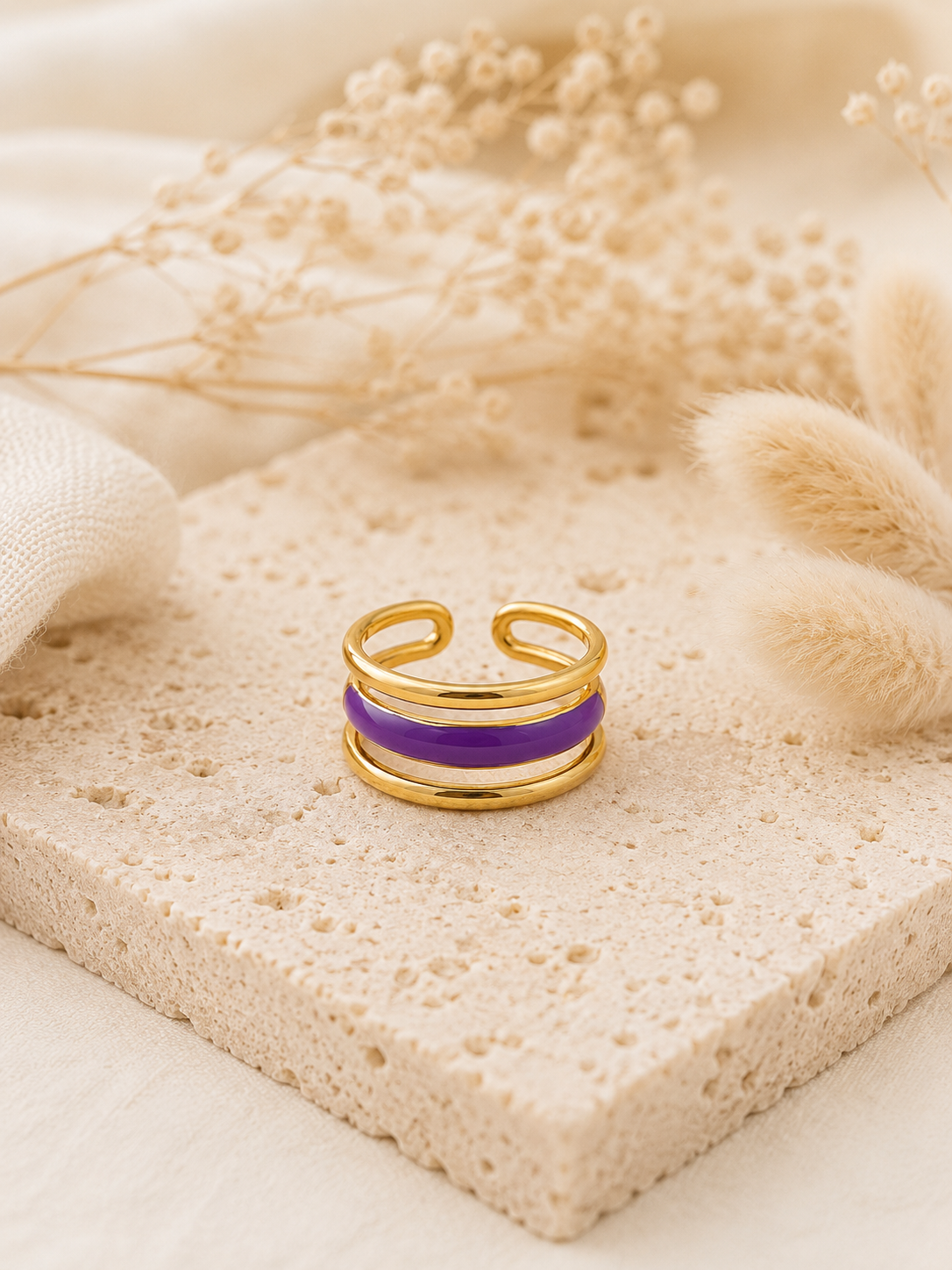 Bague Veha dorée et violette posée sur pierre beige texturée dans une ambiance douce et naturelle – Bella Cosa