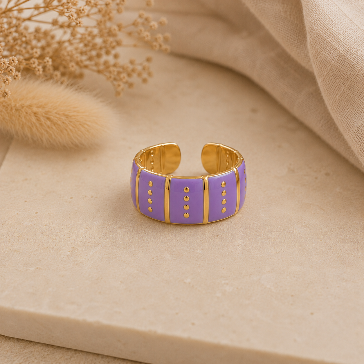 Bague Vic violette et dorée posée sur pierre beige texturée dans une ambiance chaleureuse et naturelle – Bella Cosa