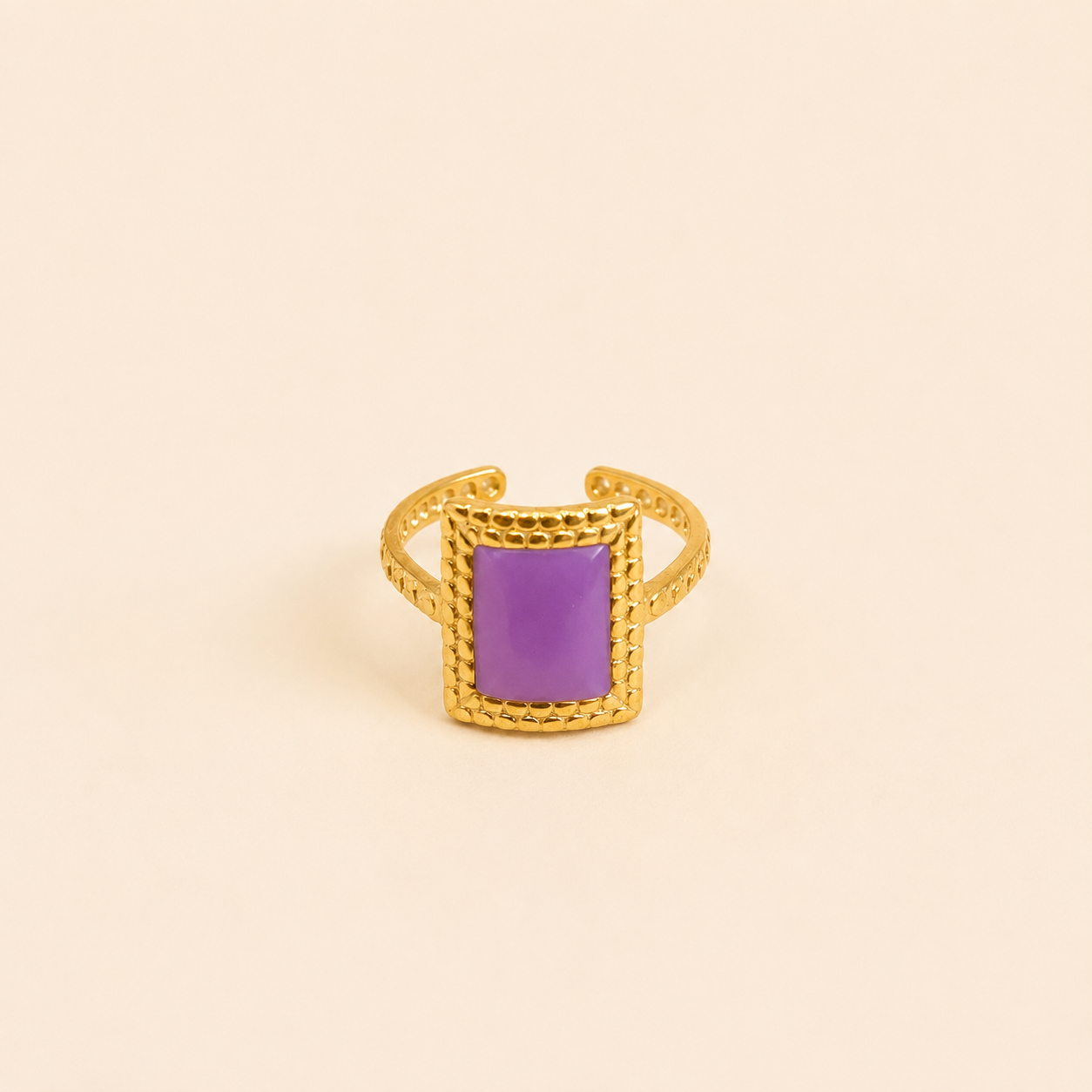Bague Vélina dorée avec pierre violette rectangulaire sur fond crème minimaliste – bijou femme élégant Bella Cosa