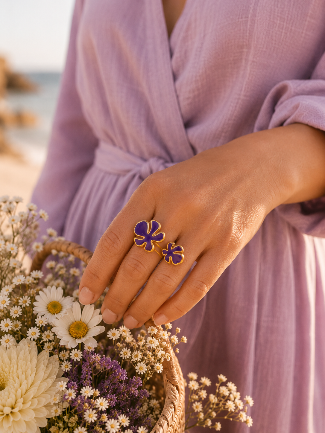 Main portant la bague Vélina dorée avec pierre violette dans une ambiance chic et moderne aux tons beige et doré – bijou femme Bella Cosa