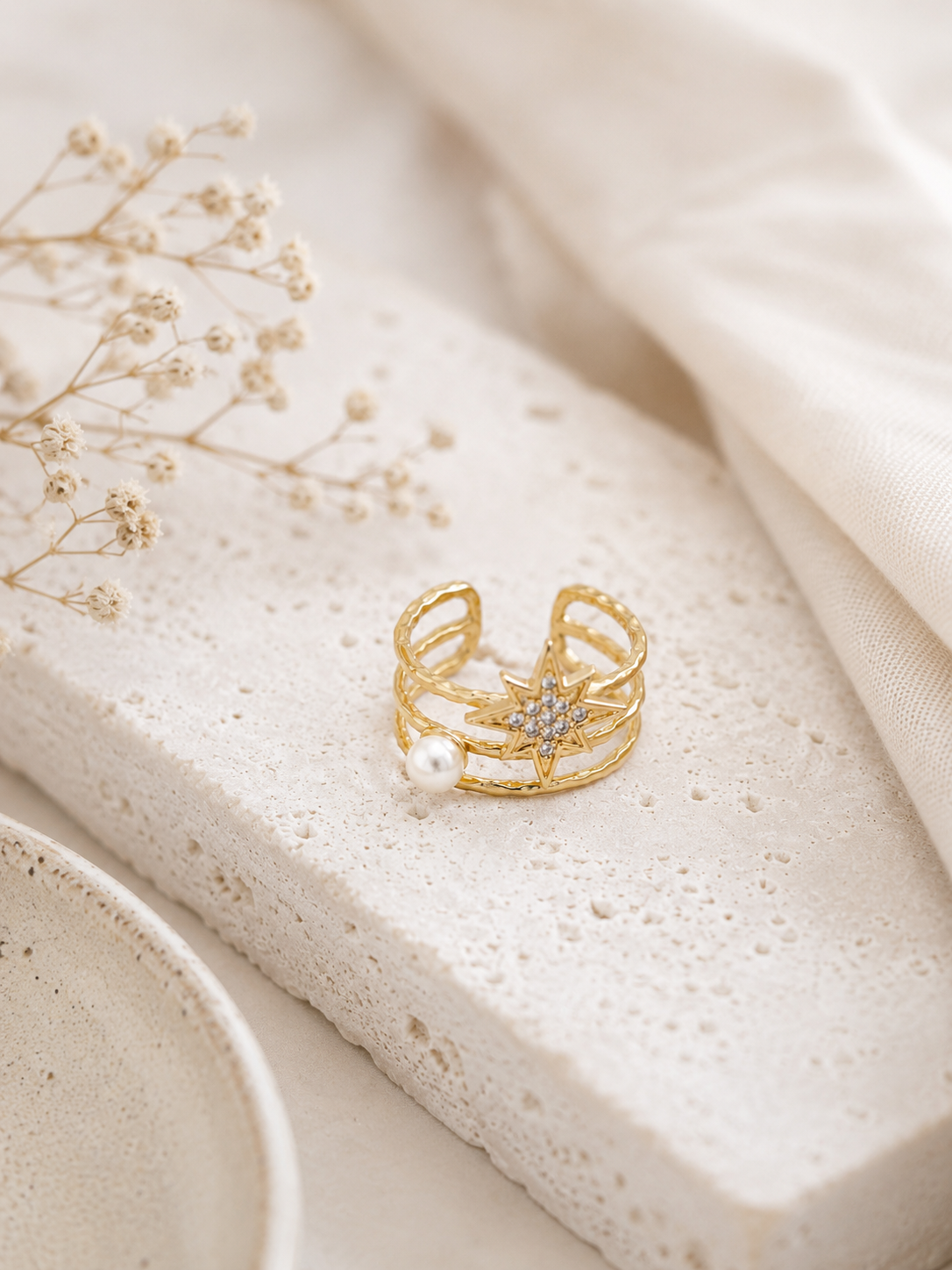 Main portant la bague Anna dorée avec étoile et perle blanche sur pull mohair crème dans une ambiance cosy et élégante – bijou femme Bella Cosa