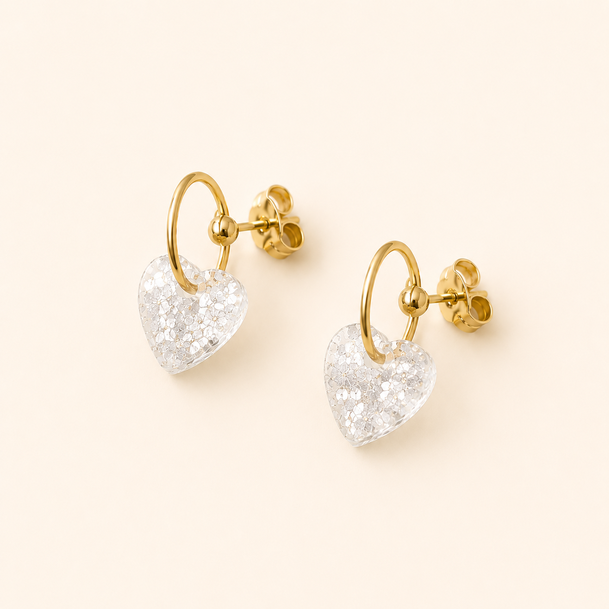 Boucles d’oreilles Cassie blanc glacier avec cœur translucide pailleté sur fond beige doux
