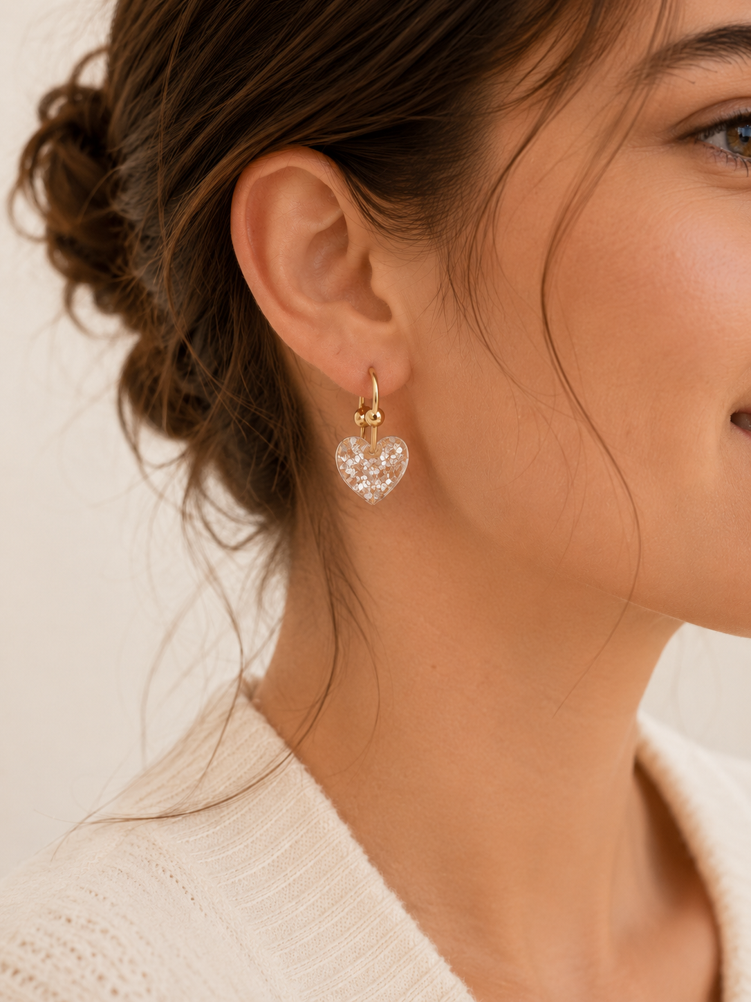 Boucles d’oreilles Cassie blanc glacier avec cœur translucide pailleté portées en lumière naturelle