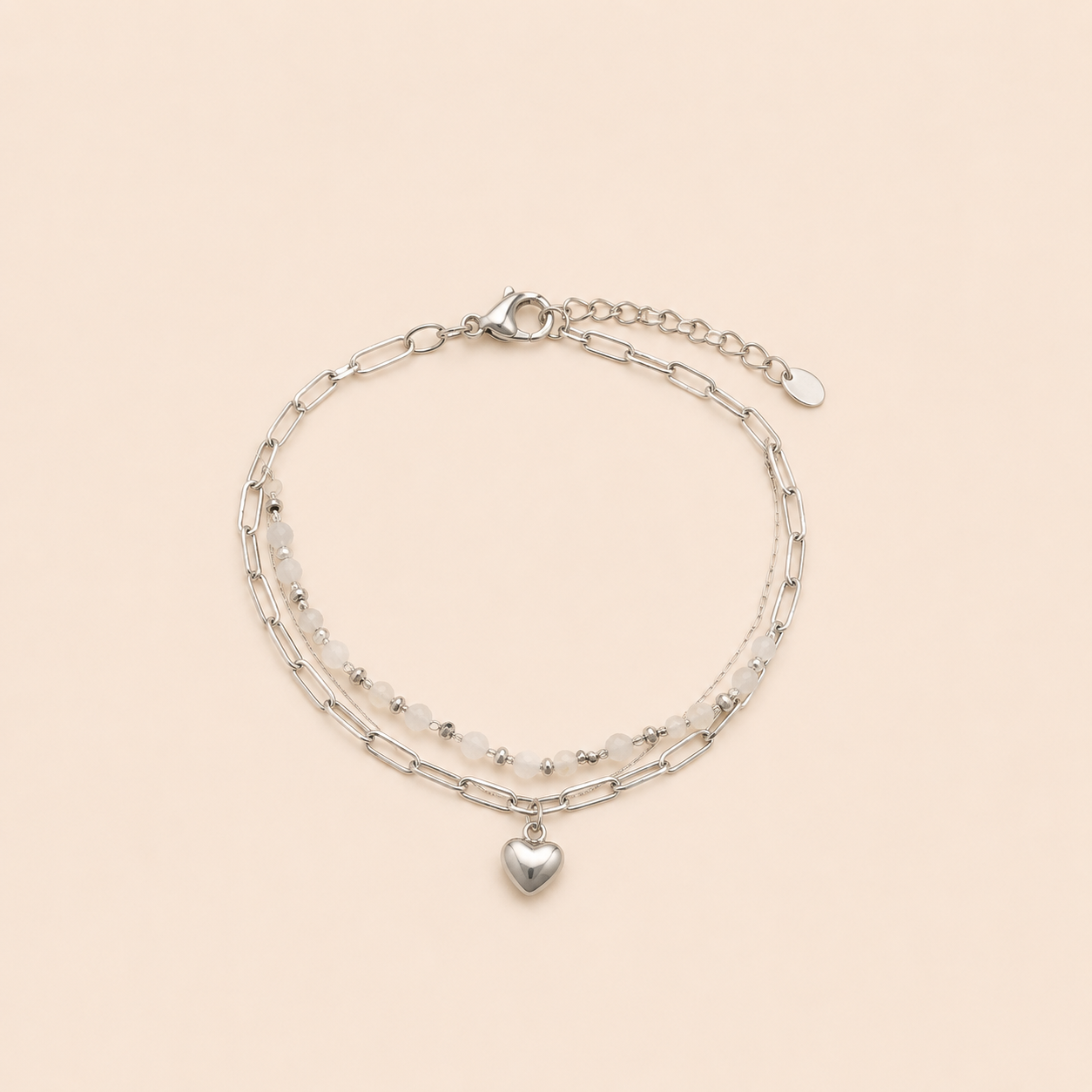 Bracelet April argenté double rang avec perles blanches et pendentif cœur sur fond crème minimaliste