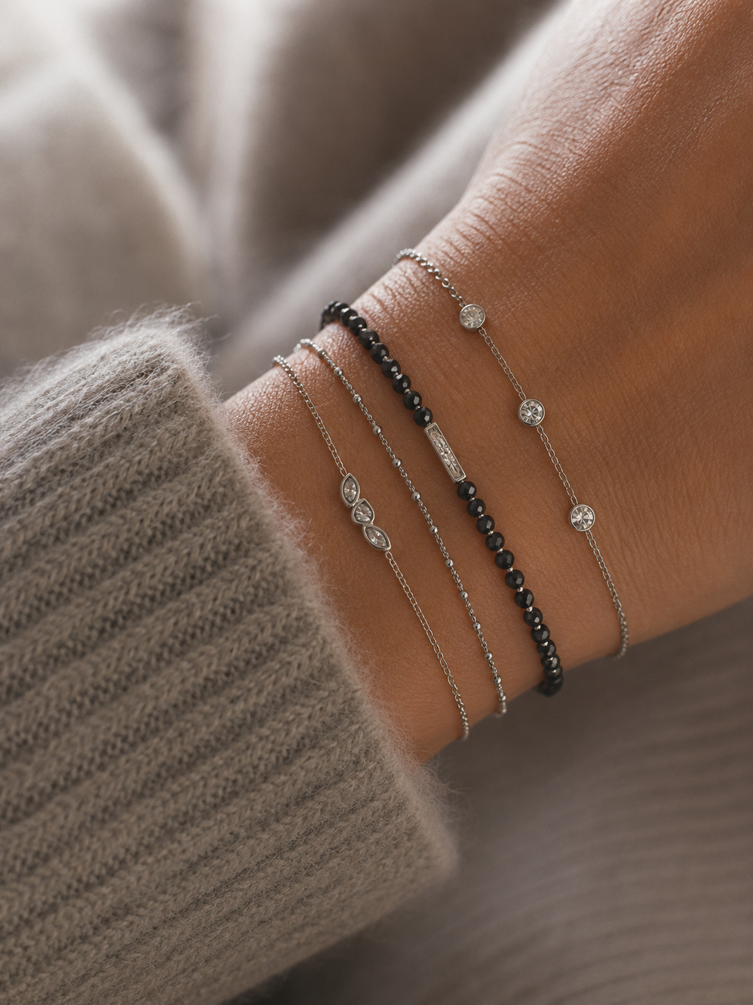 Bracelet Célestine argenté avec trois zirconiums marquise porté sur un poignet féminin en maille douce gris taupe