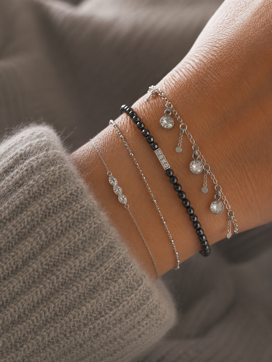 Bracelet Cerise argenté avec pampilles cristaux lumineux porté sur un poignet féminin avec maille douce beige et ambiance cosy raffinée