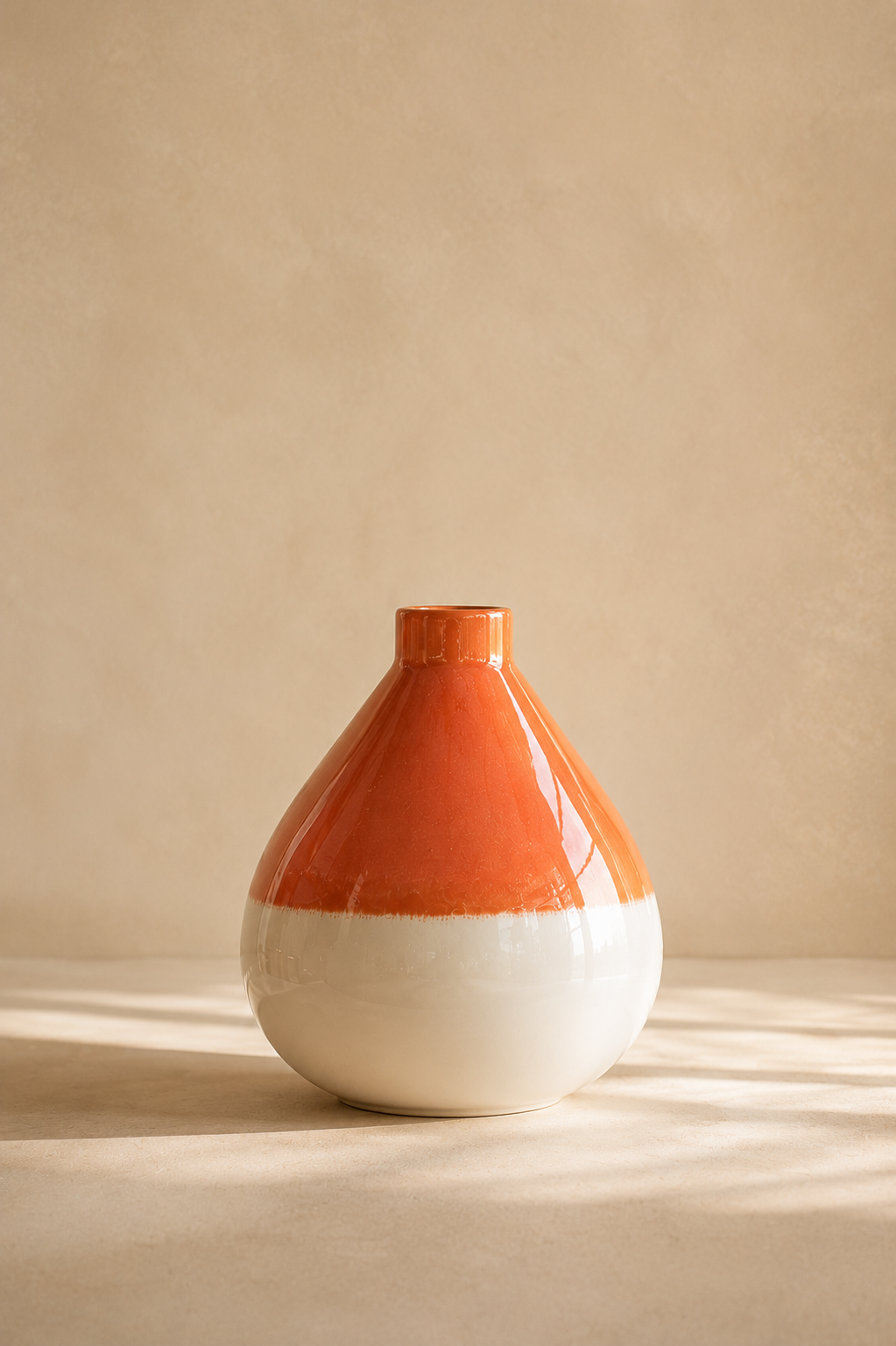 Vase en céramique terracotta et écru sur fond beige minimaliste avec lumière naturelle douce