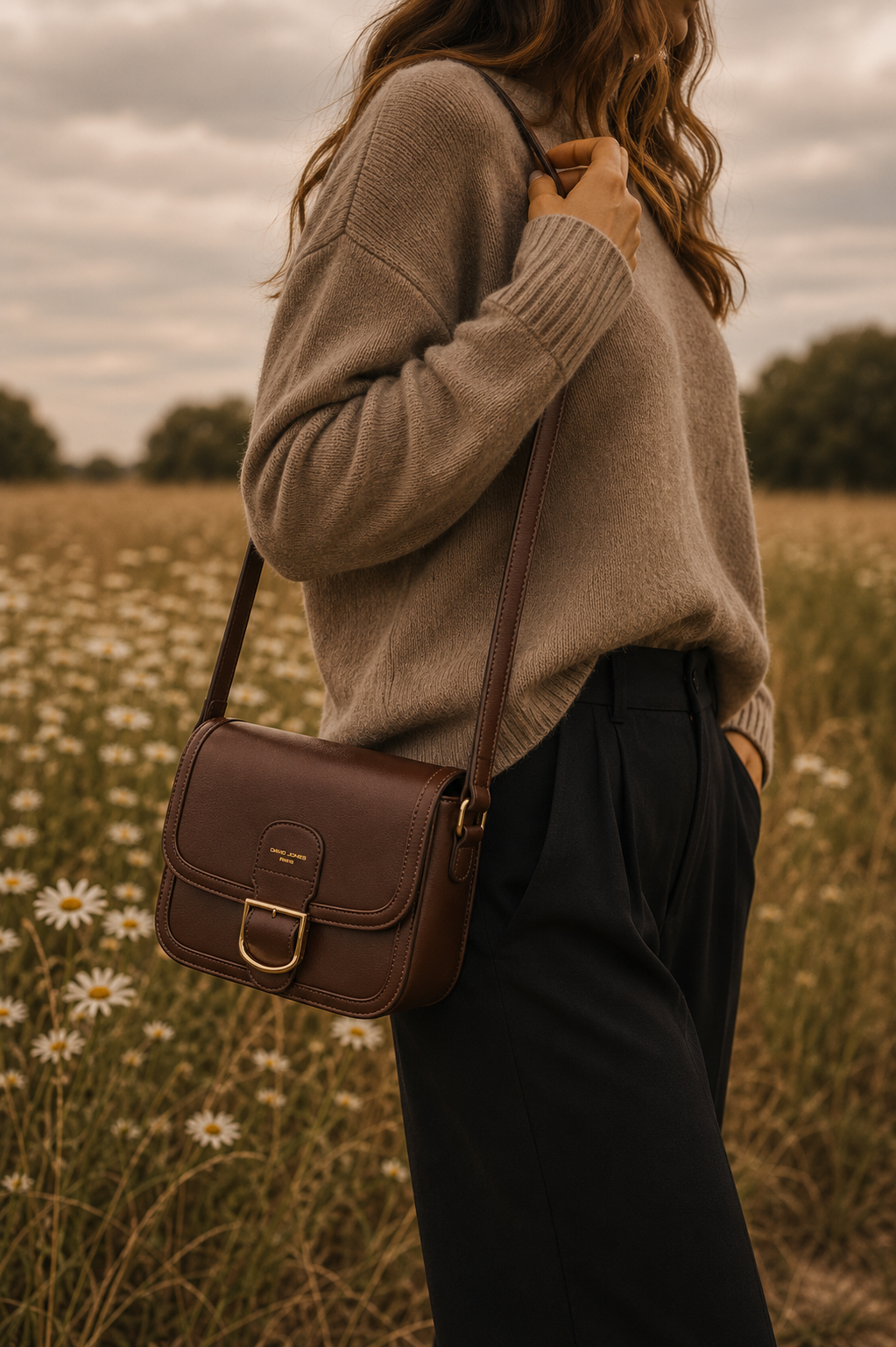 Femme portant le sac bandoulière marron Amy en similicuir lisse avec boucle dorée dans un paysage naturel élégant et chaleureux