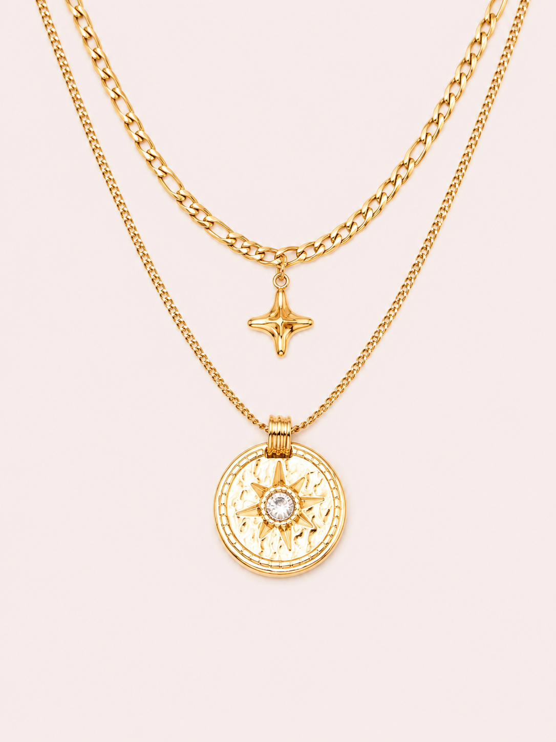 Collier Patti double chaîne dorée avec pendentif astral et pierre blanche sur fond rose poudré minimaliste