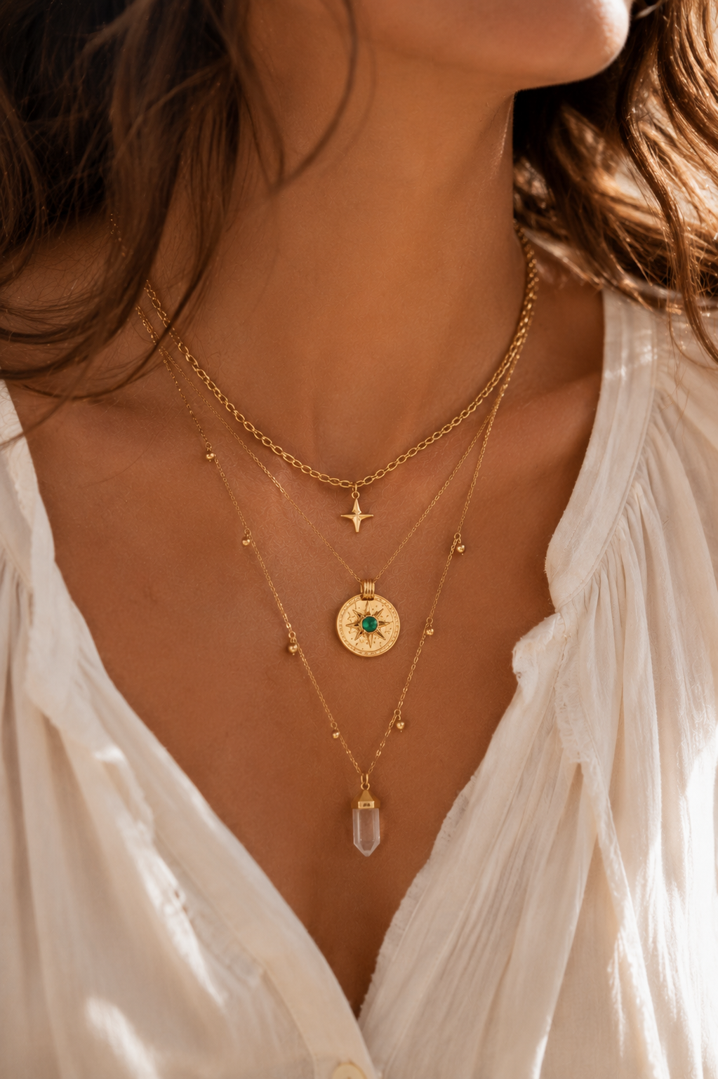 Femme portant le collier Patti double chaîne dorée avec pendentif astral et pierre verte dans une ambiance bohème chic lumineuse et élégante