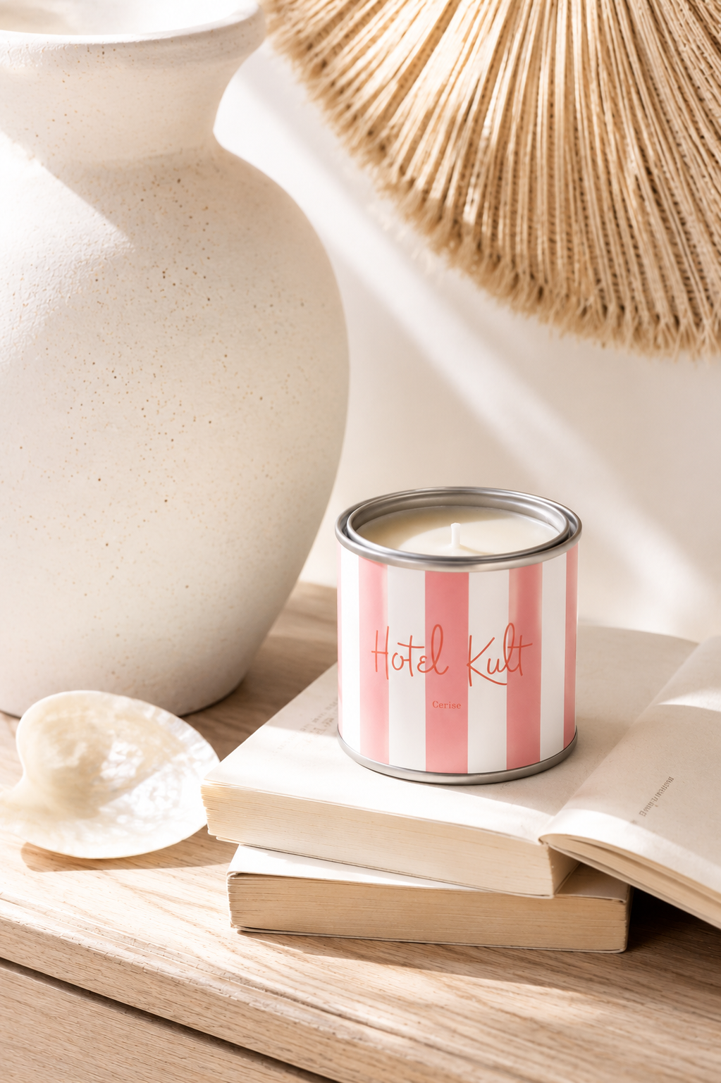 Bougie artisanale parfumée senteur cerise dans un pot style peinture rayé rose et blanc posée sur des livres dans une décoration chaleureuse et lumineuse slow living