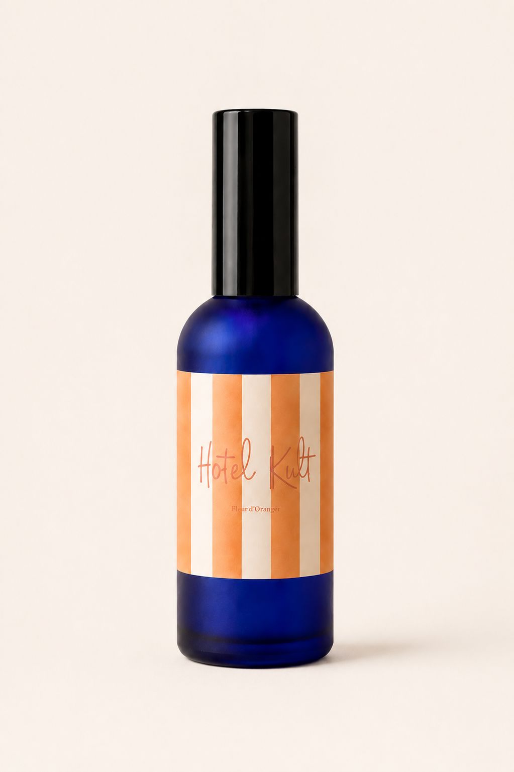 Brume de maison senteur fleur d’oranger en verre bleu fumé avec étiquette rayée orange et crème sur fond uni blanc chaud minimaliste