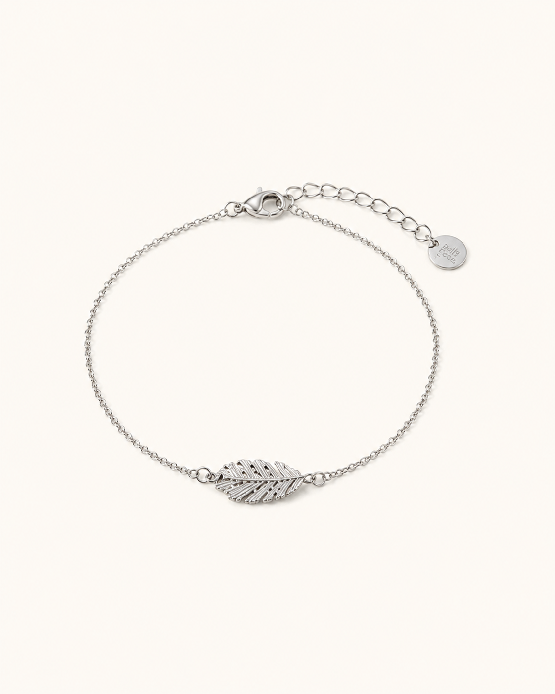 Bracelet Flora argenté en acier inoxydable avec motif feuille sur fond beige clair, idéal pour découvrir les détails du bijou.