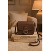 Sac bandoulière marron Amy en similicuir lisse posé sur des livres dans un intérieur cosy aux tons crème et caramel