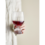 Verre à vin artisanal soufflé bouche, rempli de vin rouge. Mise en situation pour une ambiance de table chaleureuse et élégante.