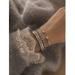 Accumulation de bracelets joncs argentés portés avec pull maille et dentelle élégante