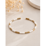 Jonc Abby blanc et doré en acier inoxydable au design minimaliste et élégant sur tissu beige texturé dans une ambiance chaleureuse et raffinée