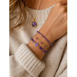 Accumulation de bracelets lilas et dorés portés avec pull crème cosy