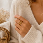 Main portant la bague Ornella dorée avec pull mohair beige dans une ambiance douce et naturelle – bijou femme Bella Cosa