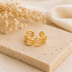 Bague Olia dorée aux motifs ovales posée sur pierre naturelle beige dans une ambiance chaleureuse et épurée – Bella Cosa