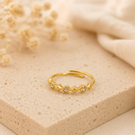 Bague Oya dorée avec cristaux posée sur pierre naturelle beige avec arrière-plan flouté – bijou femme Bella Cosa