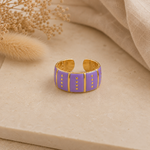 Bague Vic violette et dorée posée sur pierre beige texturée dans une ambiance chaleureuse et naturelle – Bella Cosa