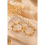 Boucles d’oreilles Alma dorées posées sur travertin et lin beige lumière naturelle chaleureuse