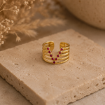 Bague Venda dorée avec pierres roses posée sur travertin beige dans une ambiance chaleureuse et naturelle – Bella Cosa