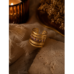 Bague Valéria dorée avec détails violets posée sur pierre beige et tissu naturel dans une ambiance cosy et chaleureuse – Bella Cosa