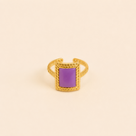 Bague Vélina dorée avec pierre violette rectangulaire sur fond crème minimaliste – bijou femme élégant Bella Cosa