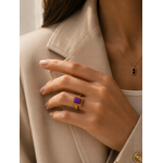 Main portant la bague Vélina dorée avec pierre violette dans une ambiance chic et moderne aux tons beige et doré – bijou femme Bella Cosa