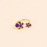 Bague Vélina dorée et violette posée sur travertin beige et tissu naturel dans une ambiance chaleureuse et raffinée – Bella Cosa