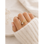 Bague Anna dorée avec étoile scintillante et perle posée sur travertin beige et lin naturel dans une ambiance douce et chaleureuse – Bella Cosa
