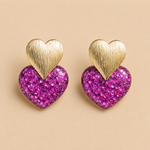Boucles d’oreilles Caroline violet fuchsia cœur pailleté doré sur fond beige élégant et féminin