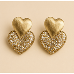 Boucles d’oreilles Caroline dorées cœur pailleté sur fond beige clair style bijou élégant et lumineux