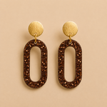 Boucles d’oreilles Clémentine moka en résine pailletée sur fond beige naturel