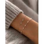 Accumulation de bracelets fins argentés avec perles blanches et pierres délicates portés sur poignet féminin – bijoux minimalistes Bella Cosa