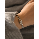 Bracelet Gizem argenté à grosses mailles avec fermoir cœur serti de zirconiums porté sur un poignet féminin en maille grise douce